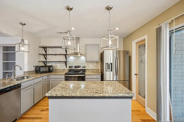 a kitchen with stainless steel appliances granite countertop a sink a refrigerator and a stove