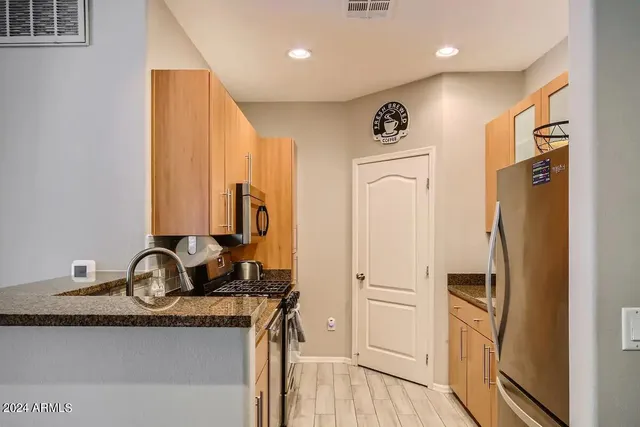 a view of kitchen with stainless steel appliances granite countertop a refrigerator and a sink