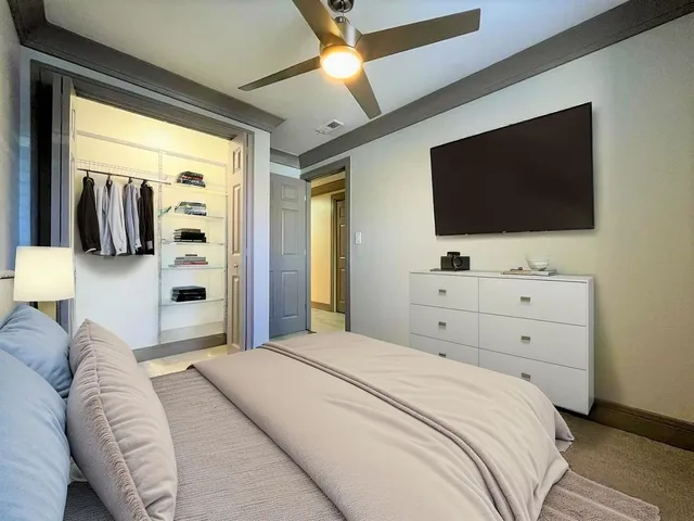 a bedroom with a bed and a flat tv screen on a dresser