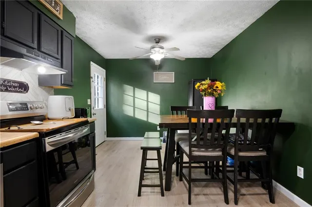 a kitchen with stainless steel appliances granite countertop a dining table chairs and a stove