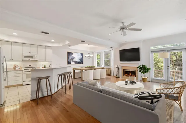 a view of an empty room with wooden floor and a kitchen