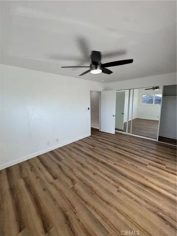 a view of a room with wooden floor and a ceiling fan