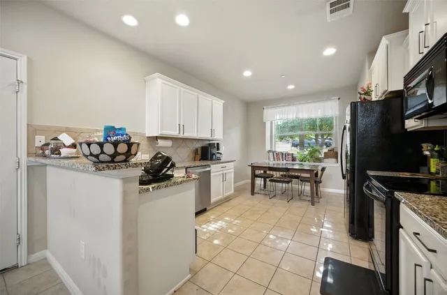 a kitchen with kitchen island granite countertop a sink cabinets and stainless steel appliances