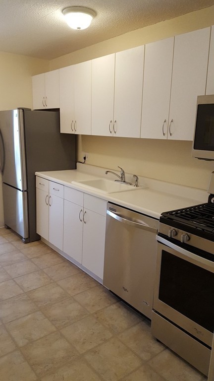44 Washington Street, Unit 411 Brookline, MA 02445 - Photo 6 of 23 a kitchen with granite countertop white cabinets and stainless steel appliances