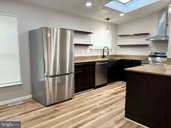 a kitchen with granite countertop a refrigerator stove and sink