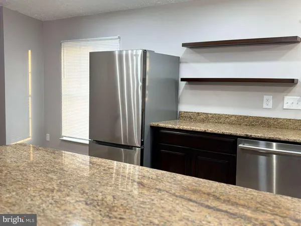 a kitchen with granite countertop a refrigerator and a stove