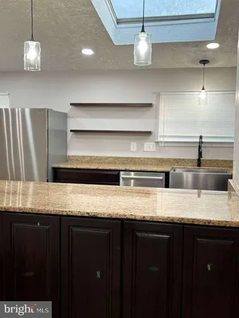 a kitchen with stainless steel appliances granite countertop a sink a refrigerator and a granite counter top