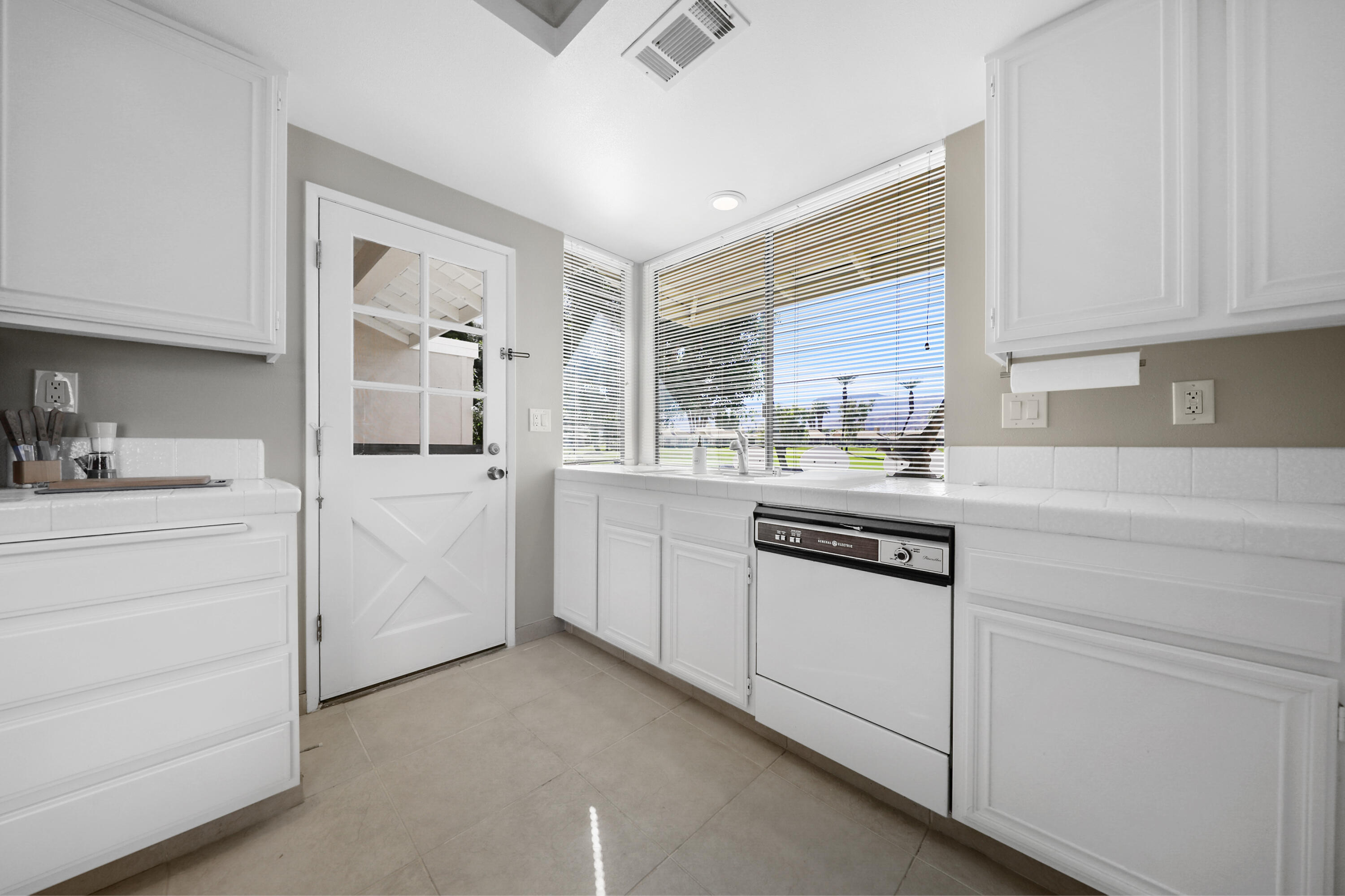 175 Gran Via Palm Desert, CA 92260 - Photo 12 of 36 a kitchen with granite countertop white cabinets and white appliances