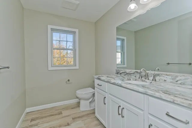a bathroom with a granite countertop toilet sink and mirror