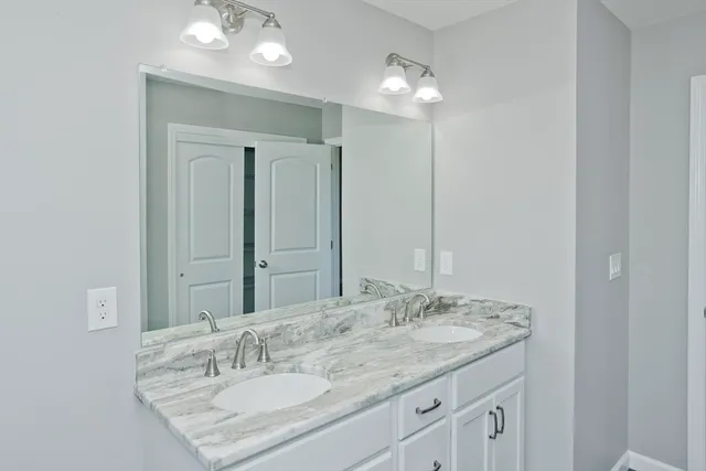 a bathroom with a granite countertop sink a light fixture and a mirror