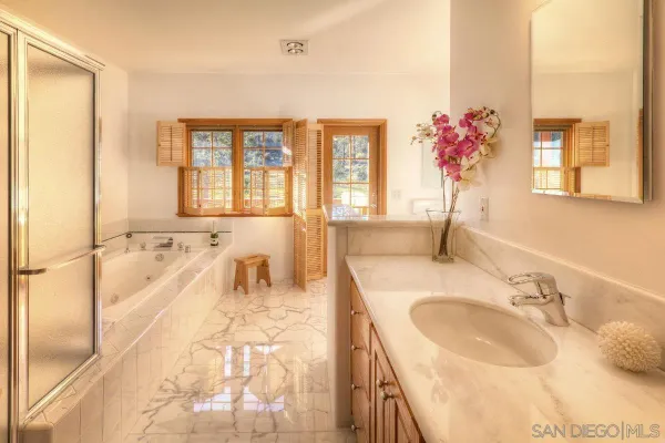 a spacious bathroom with a granite countertop double vanity sink a mirror and a bathtub