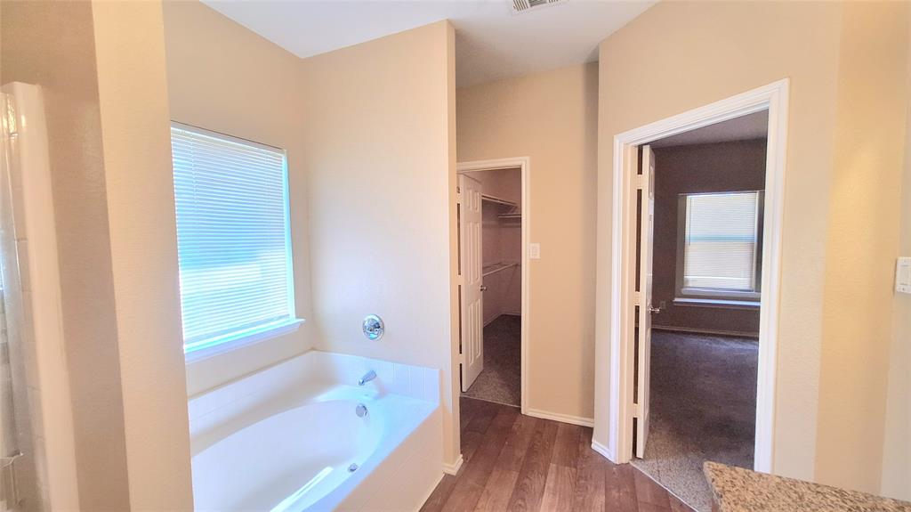 953 Hannah Way Dallas, TX 75253 - Photo 16 of 22 Soaking tub with chrome fixtures, window with blinds, wood-finish flooring, and light neutral wall tones