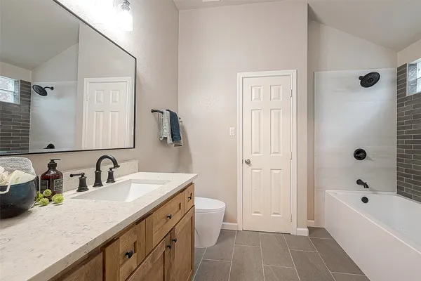 a bathroom with a tub sink double vanity and a mirror