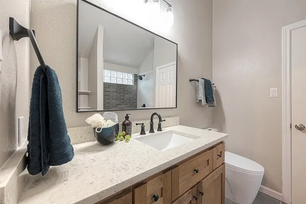 a bathroom with a sink a toilet a mirror and shower