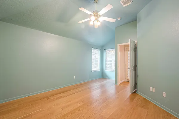 an empty room with wooden floor and a ceiling fan