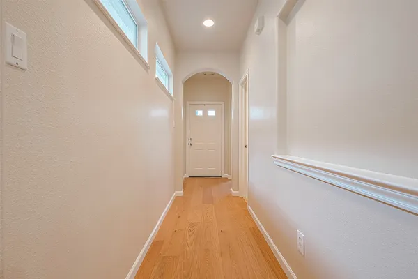 a view of a hallway with wooden floor and a bathroom