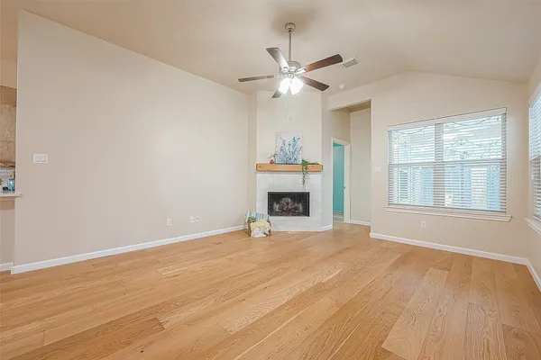 a view of empty room with wooden floor and fan