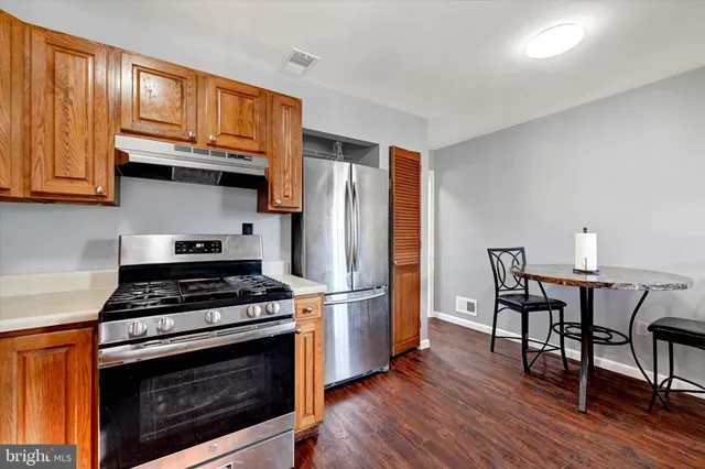 a kitchen with stainless steel appliances a stove a refrigerator and wooden floors