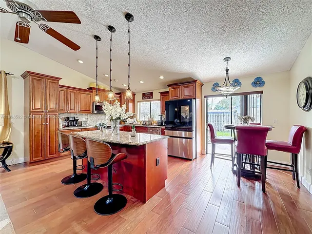 a kitchen with stainless steel appliances granite countertop a dining table chairs stove a refrigerator and kitchen view