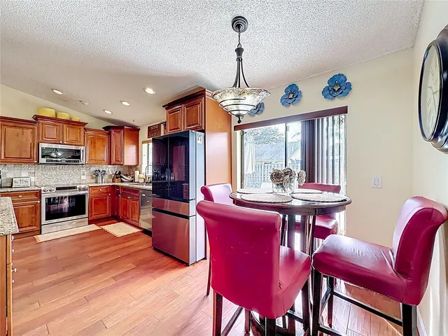 a kitchen with stainless steel appliances granite countertop a stove a refrigerator a kitchen island a dining table and chairs