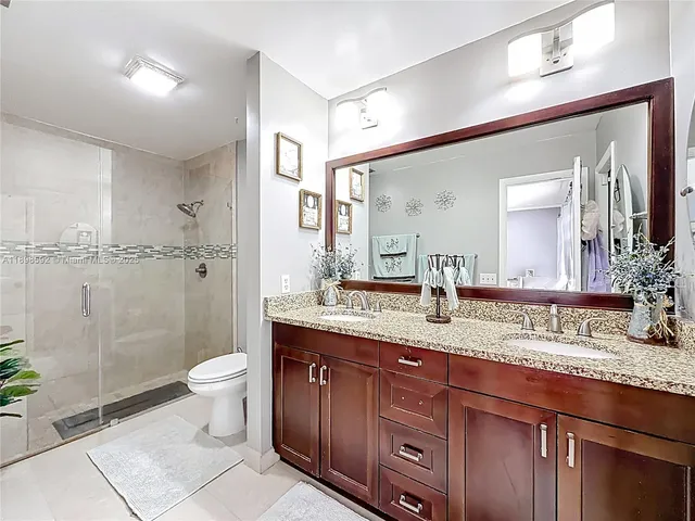 a bathroom with a granite countertop sink a toilet a mirror and shower