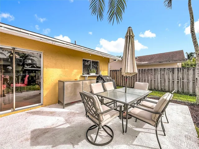 a patio with a table and chairs and potted plants