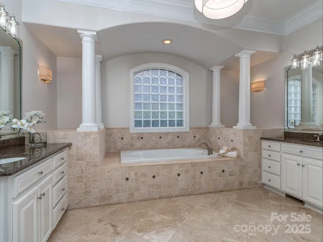a spacious bathroom with double sink a large mirror and a bathtub