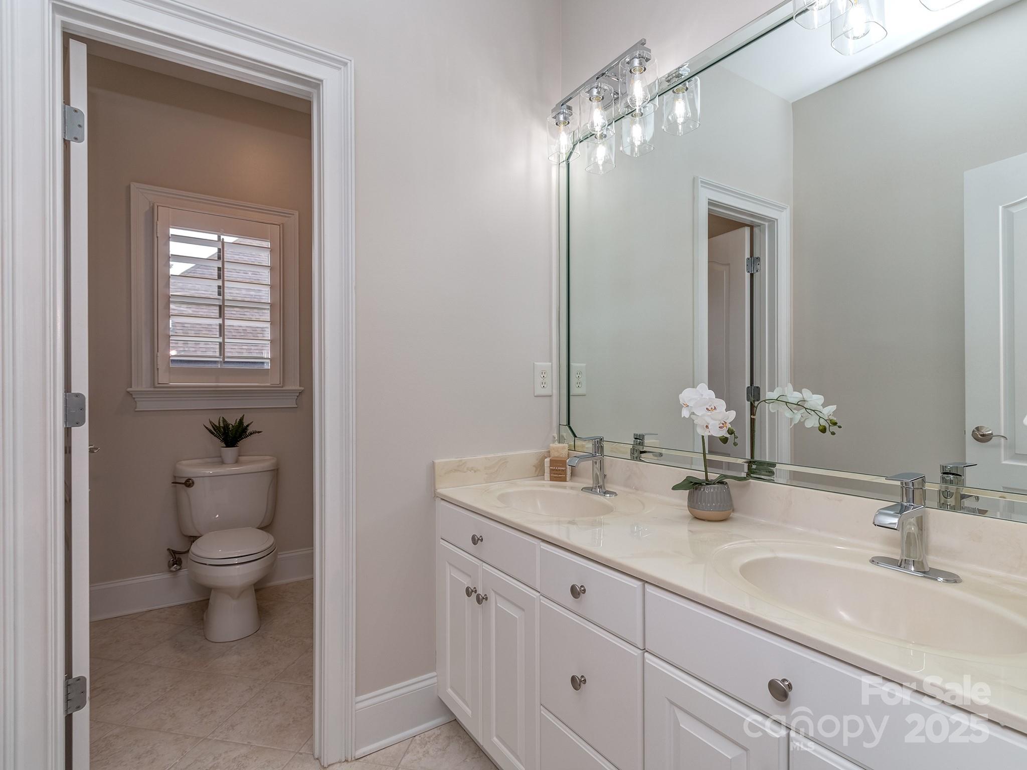 8208 Wingard Road Waxhaw, NC 28173 - Photo 29 of 41 a bathroom with double vanity sinks a toilet and a mirror