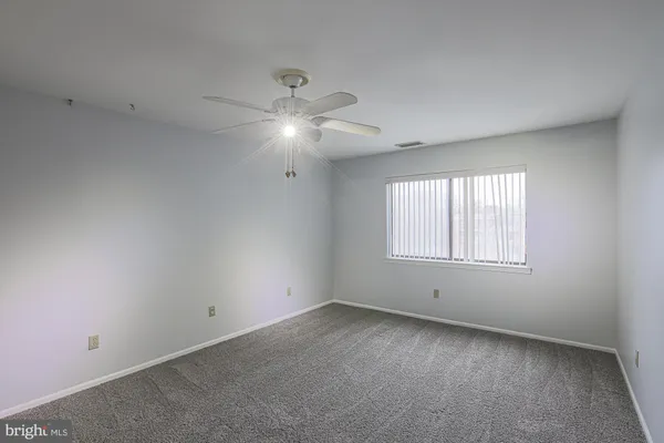 an empty room with a window and ceiling fan
