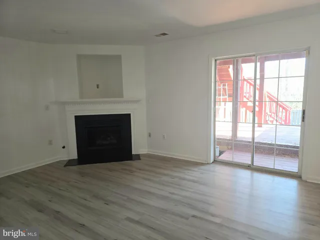 a view of empty room with wooden floor and fireplace