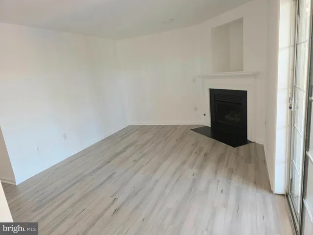 a view of empty room with wooden floor and fireplace