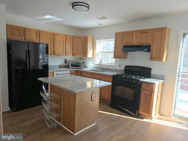 a kitchen with granite countertop a refrigerator stove and sink