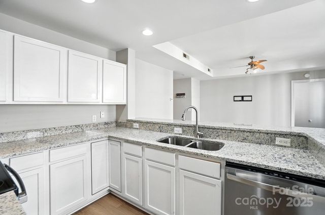 a kitchen with granite countertop white cabinets and a sink