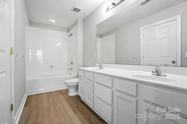 a bathroom with a double vanity sink toilet mirror and bathtub