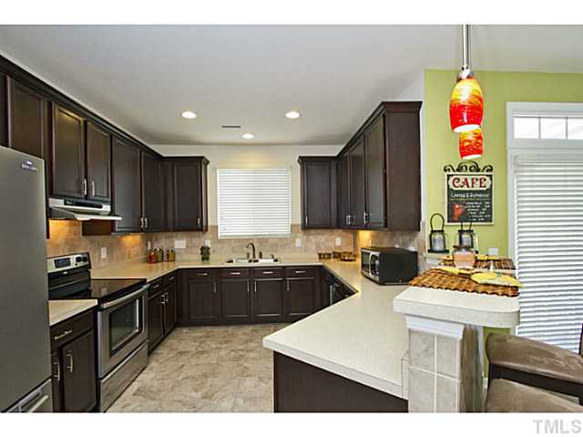 1802 Affirmed Way Cary, NC 27519 - Photo 5 of 24 a kitchen with kitchen island granite countertop a sink counter top space appliances and cabinets