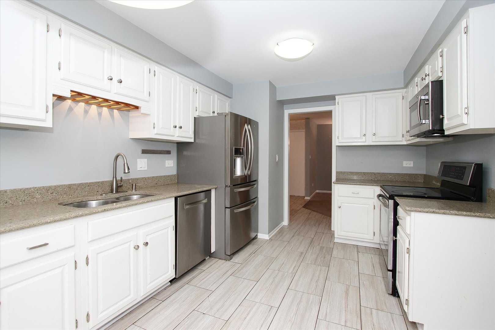 299 Mallard Point, Unit D Lake Barrington, IL 60010 - Photo 6 of 30 a kitchen with a sink a refrigerator a stove and white cabinets