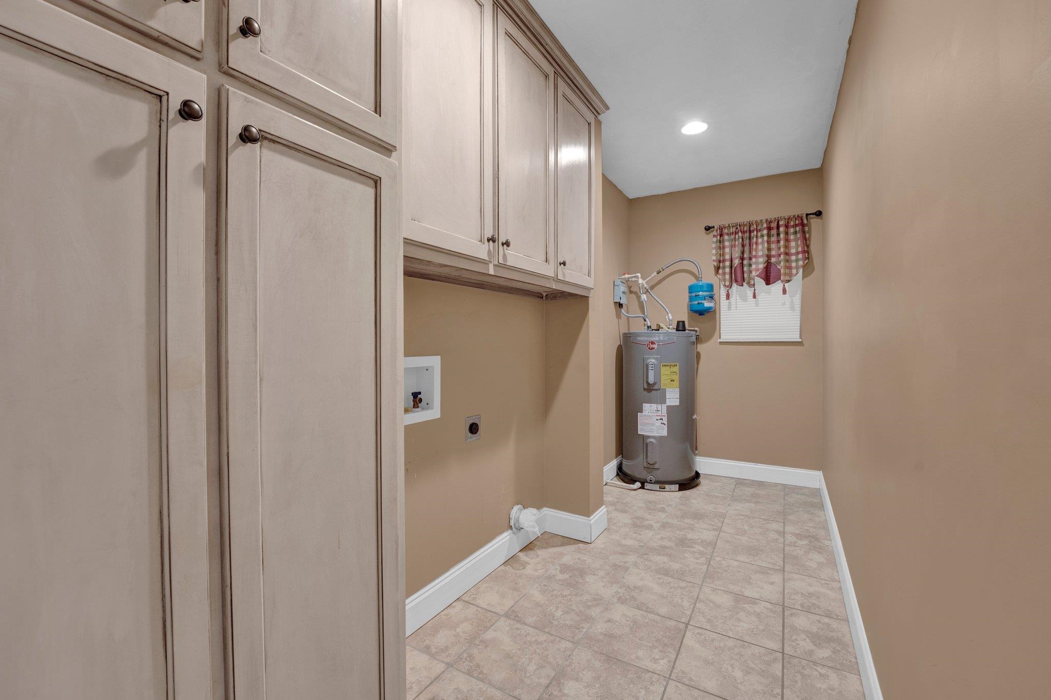 1060 Beaver Creek Road Brighton, TN 38011 - Photo 17 of 40 Laundry area featuring cabinets, washer hookup, hookup for an electric dryer, water heater, and light tile patterned floors