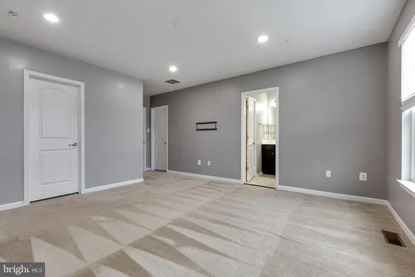 a view of an empty room with wooden floor and windows