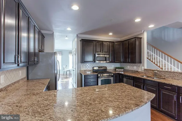 a kitchen with stainless steel appliances granite countertop a sink stove and refrigerator