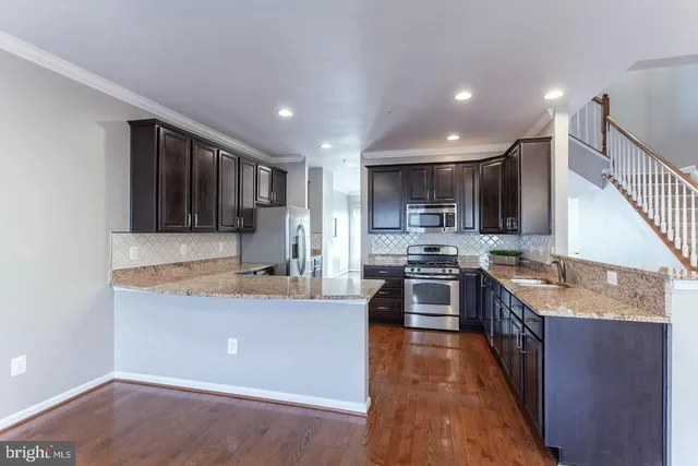 a large kitchen with stainless steel appliances granite countertop a stove a sink dishwasher a refrigerator and a oven with wooden floor