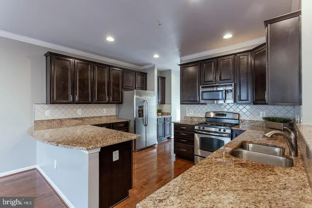 a kitchen with stainless steel appliances granite countertop a sink stove microwave and refrigerator