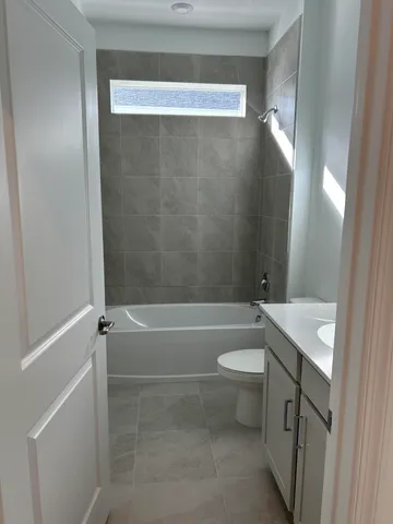 a bathroom with a granite countertop bathtub shower sink vanity and toilet