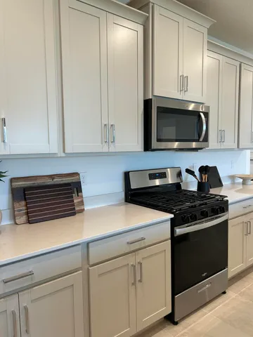 a kitchen with granite countertop white cabinets and stainless steel appliances