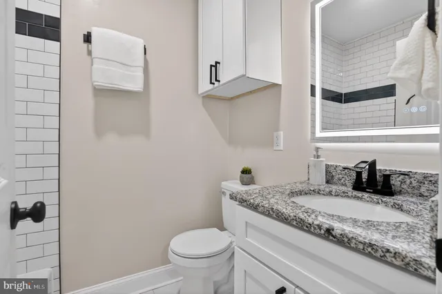 a bathroom with a granite countertop toilet sink and mirror
