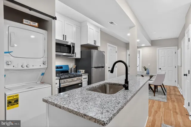 a kitchen with stainless steel appliances granite countertop a sink a stove and cabinets