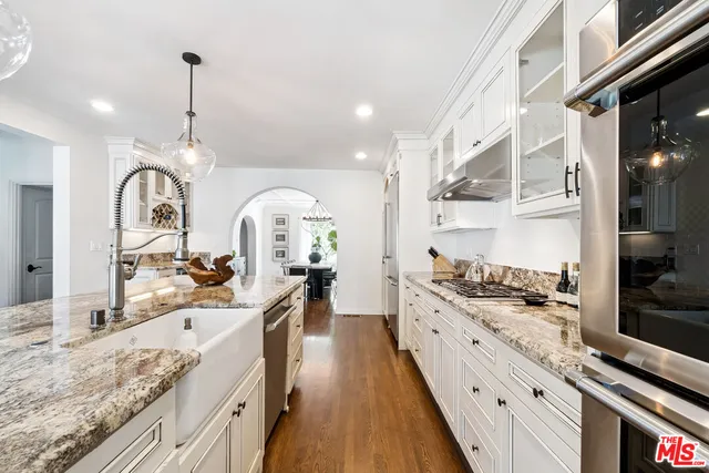 a large kitchen with stainless steel appliances kitchen island granite countertop a lot of counter space and wooden floor