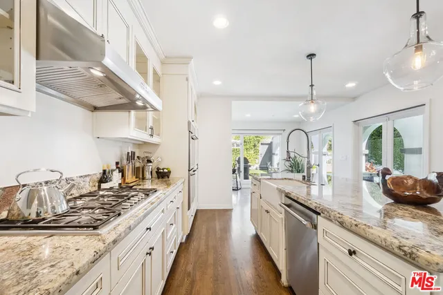a large kitchen with granite countertop a large counter top a sink stainless steel appliances and cabinets