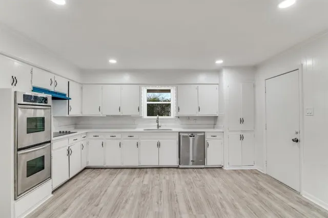 a kitchen with granite countertop white cabinets and stainless steel appliances