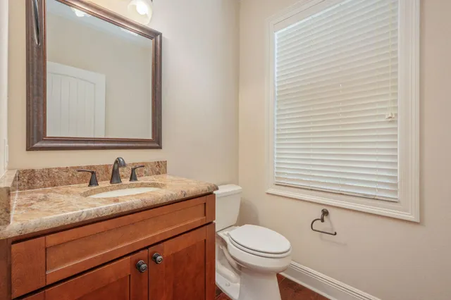 a bathroom with a granite countertop toilet sink and mirror