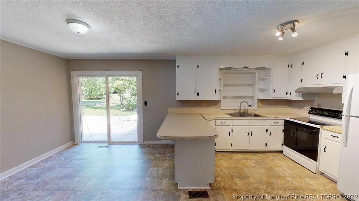 7608 Decatur Drive Fayetteville, NC 28303 - Photo 11 of 36 a kitchen with a stove a sink and white cabinets